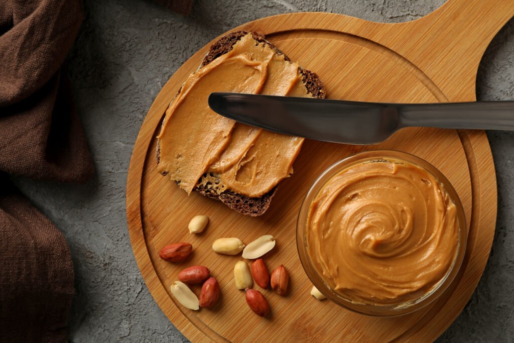 concept of tasty breakfast with peanut and peanut butter on gray