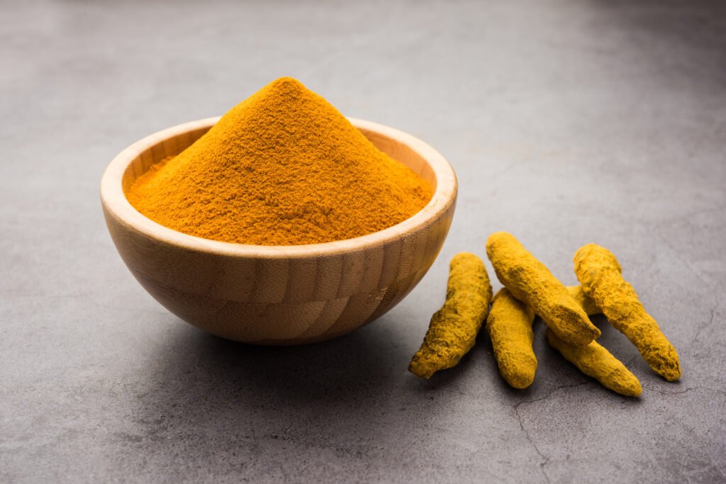 organic haldi or turmeric powder spice pile in a bowl with whole, selective focus